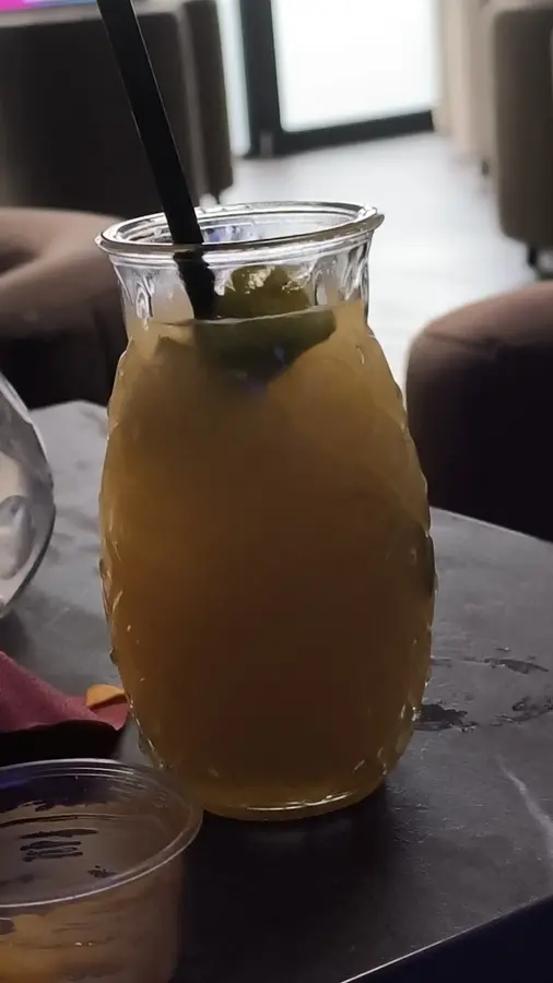 Gelber Cocktail im Glas mit Rautenmuster auf einem Tisch in der Lounge